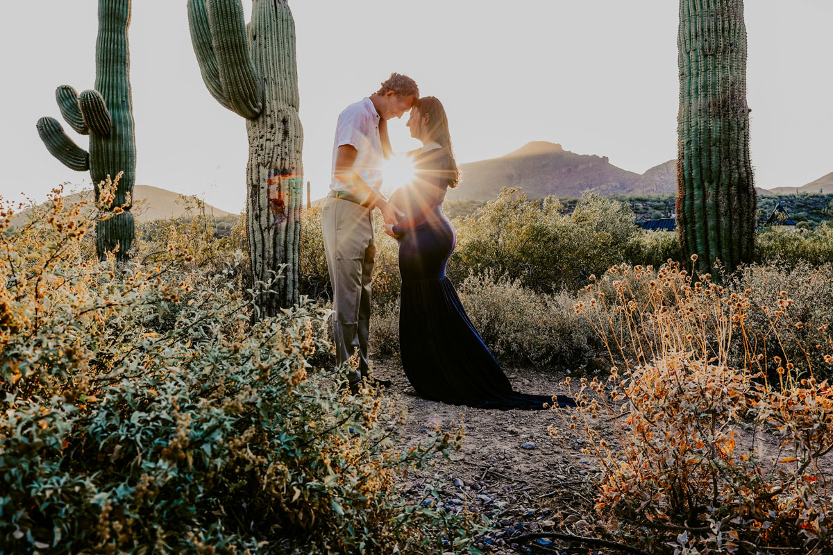Man and wife looking at each other while their foreheads touches with a desert background.