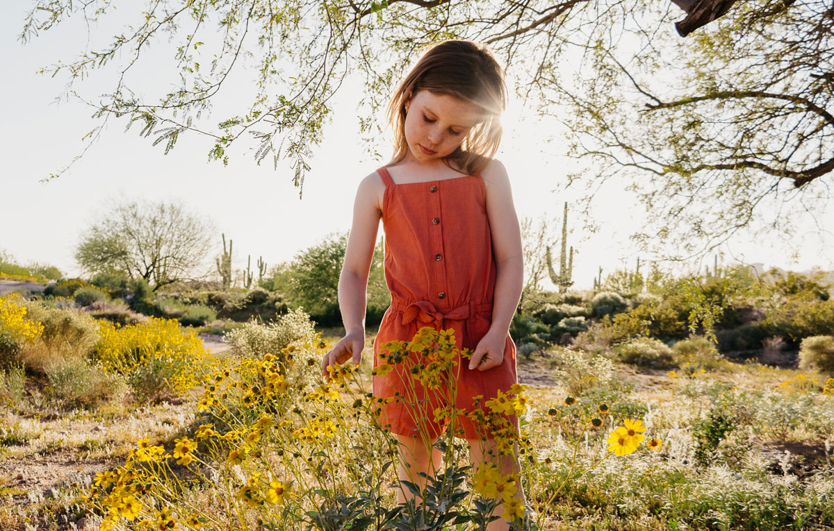 Young girl looking at yellow flowers with a sunny background