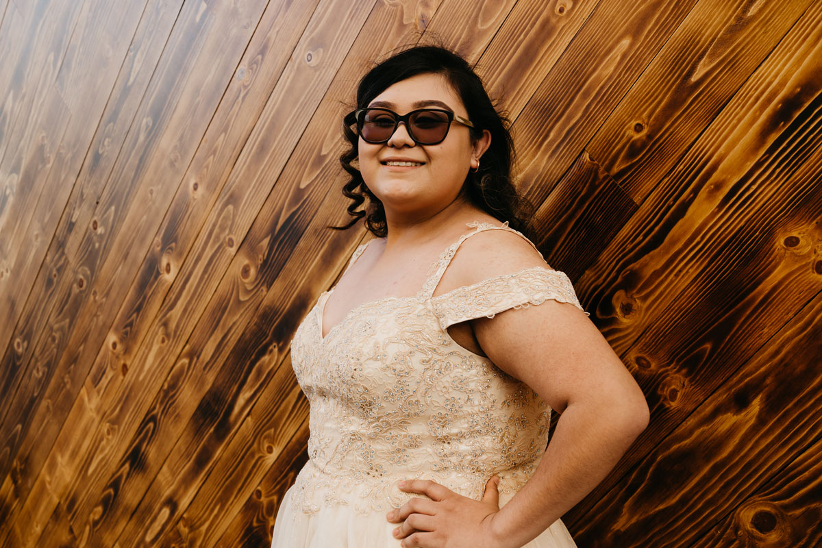 Young lady wearing a white dress against a wooden background