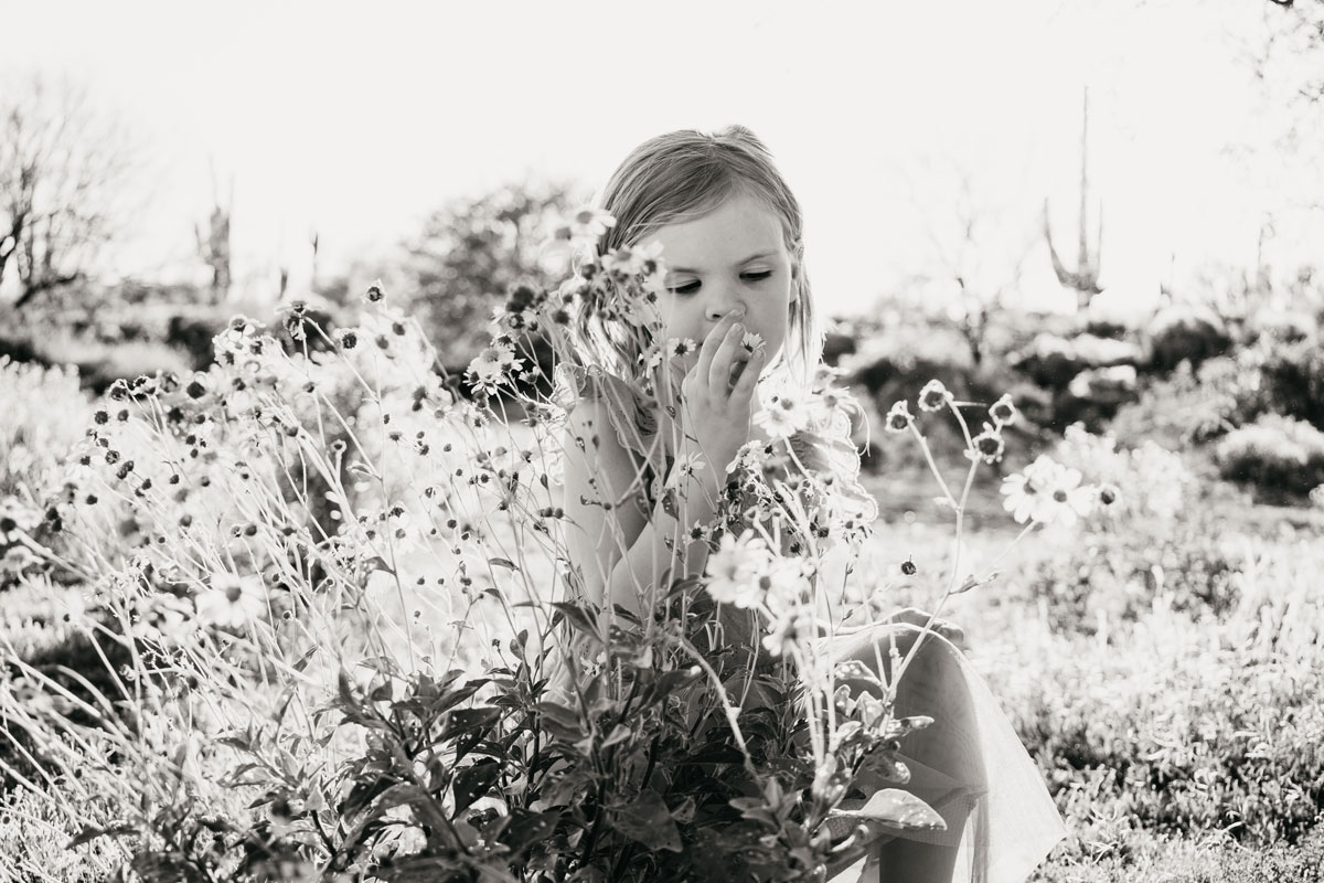 Black and white photograph of a young girl smelling flowers.